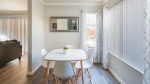 A dining area with a white table, four chairs, and a small potted plant. - Pearl of Scottsdale Old Town Getaway 1BR (Scottsdale)