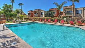 A swimming pool with red lounge chairs and palm trees, surrounded by modern buildings. - Pearl of Scottsdale Old Town Getaway 1BR (Scottsdale)