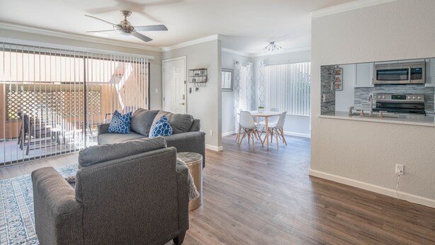 A spacious living room with a gray sofa, a dining area with a white table and chairs, and a kitchen with modern appliances. - Pearl of Scottsdale Old Town Getaway 1BR (Scottsdale)