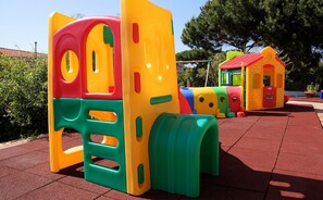 A playground with colorful play structures including a slide and a small building.
