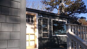 Un pequeño edificio con una terraza de madera, una puerta y una ventana.