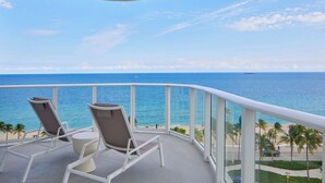 A balcony with two chairs and a table, overlooking a beach and ocean. - AC Hotel by Marriott Fort Lauderdale Beach (Fort Lauderdale)