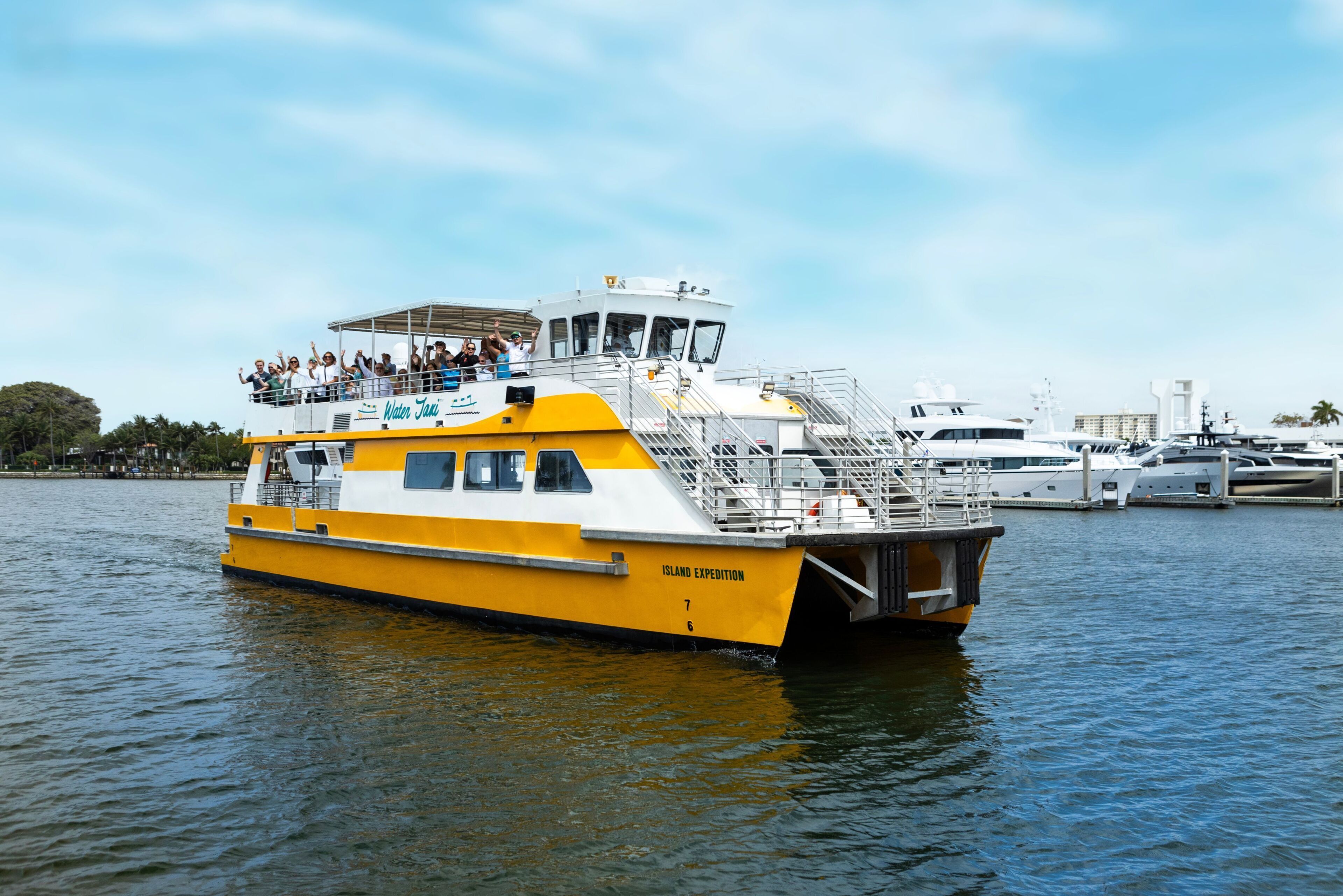 Un grand bateau jaune et blanc, sur lequel on pouvait lire les mots « Island Expedition » sur le côté, était amarré dans une marina, aux côtés d’autres bateaux.