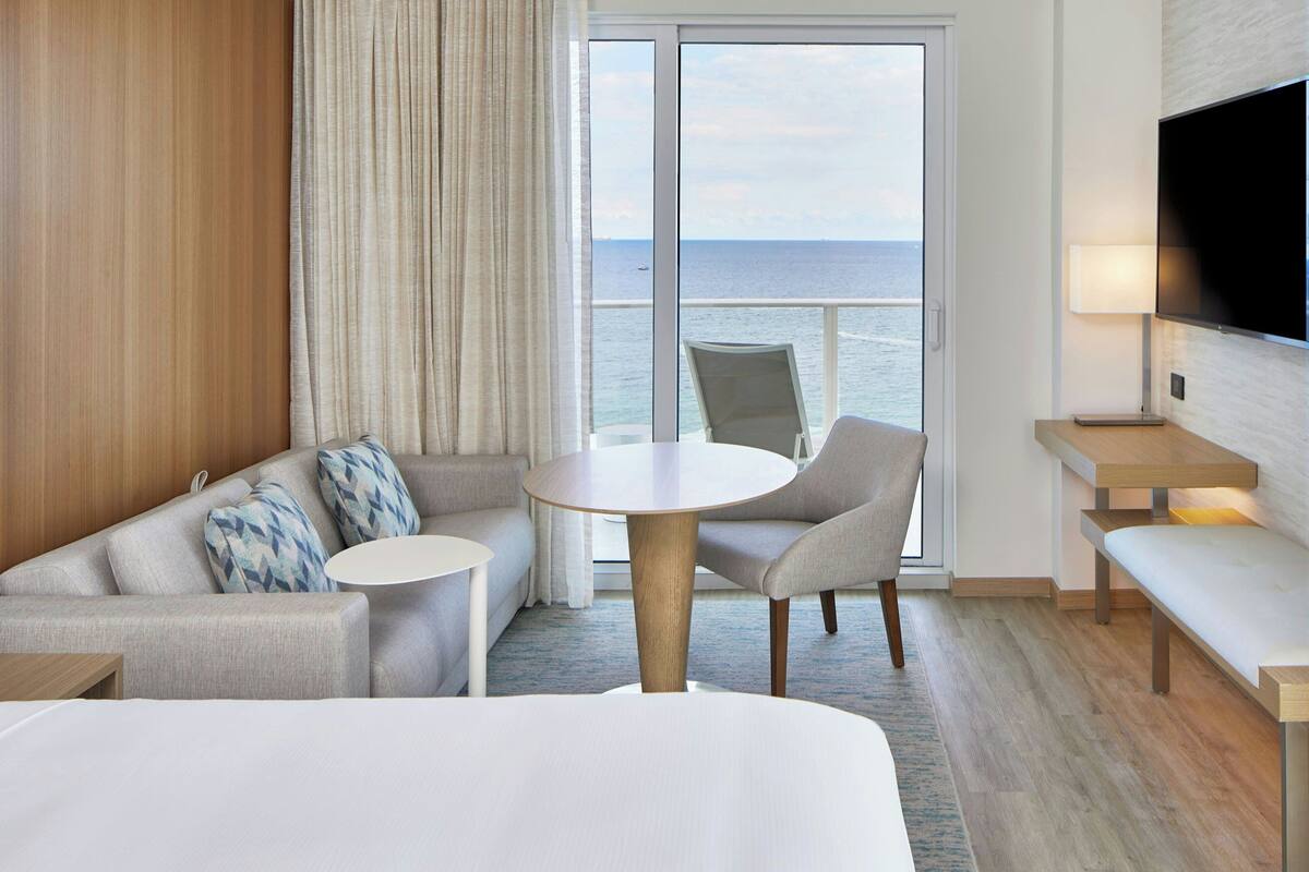 Una habitación de hotel con una cama grande, un sofá, una mesa redonda, una silla y un televisor.