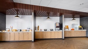 Una cocina moderna con armarios de madera, encimera blanca e iluminación colgante.