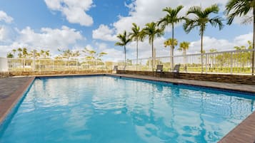 Una piscina al aire libre, sombrillas, sillones reclinables de piscina