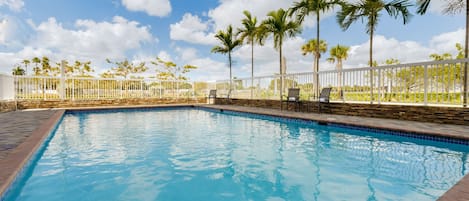 Una piscina al aire libre, sombrillas, tumbonas