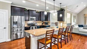A modern kitchen with dark cabinets, stainless steel appliances, and a central island with bar stools. - Luxury Villa! Backyard, 1 mile to Parkway! Hot tub & Gameroom!  (Sevierville)