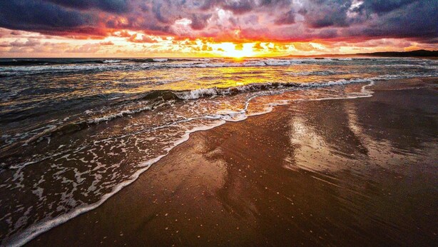 Une plage avec des vagues au coucher du soleil.