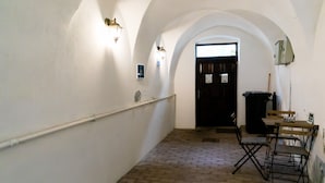 A hallway with white walls, brick flooring, and a wooden door at the end.
