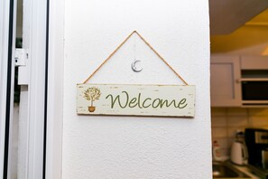 A welcome sign with a crescent moon and a potted plant on a white wall. - Tischler Apartment & Studio (Sibiu)