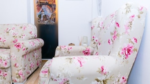A living room with floral upholstery, a framed picture on the wall, and a small table with candles.