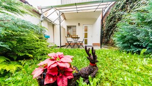 A garden with a patio, a table, and chairs.
