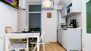 A compact kitchen with white cabinetry, a microwave, a coffee maker, and a small refrigerator.