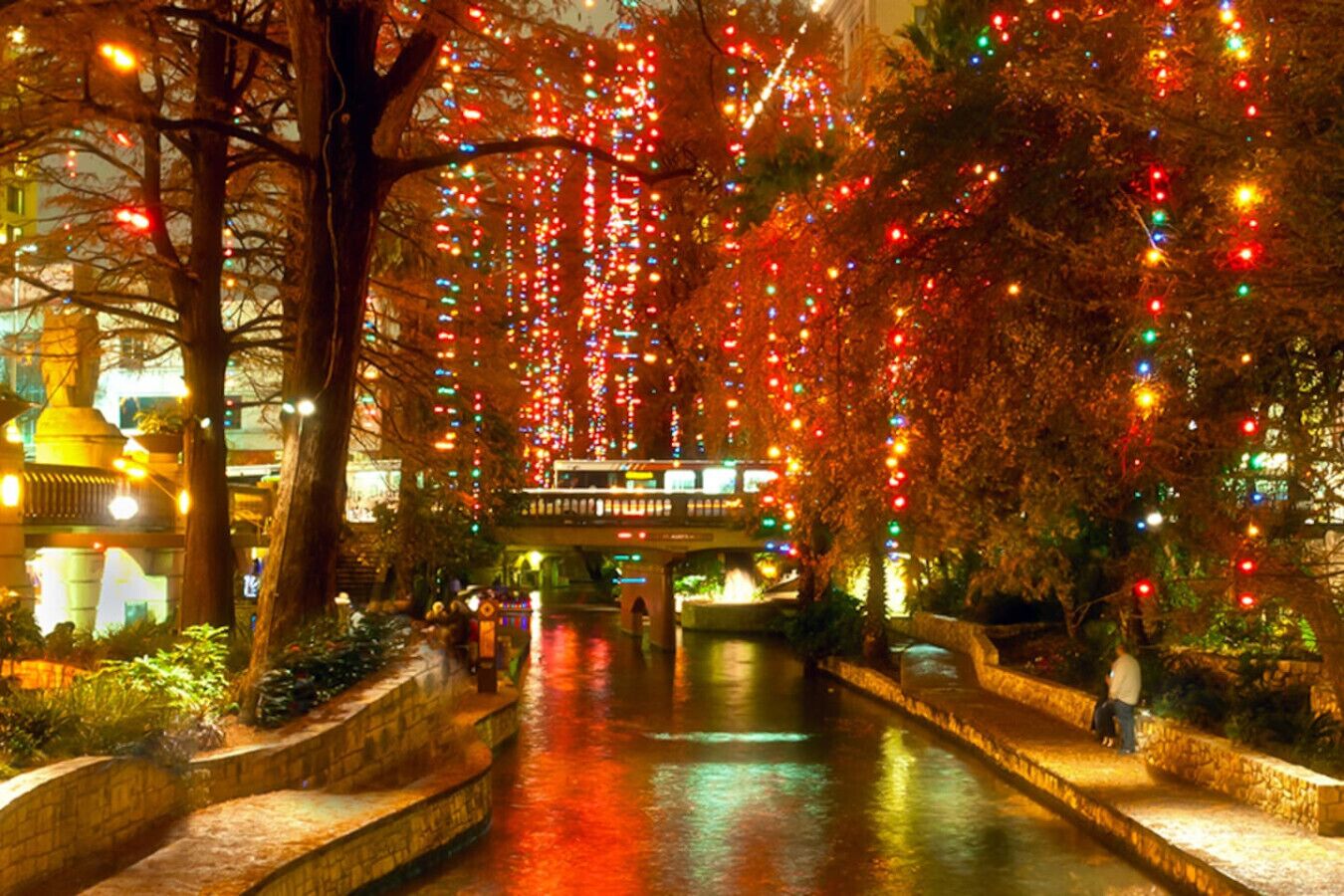 A river with stone steps, trees, and a bridge.
