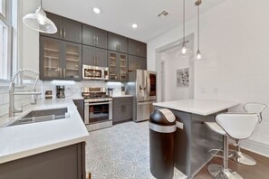 A modern kitchen with stainless steel appliances, a central island, and pendant lighting.