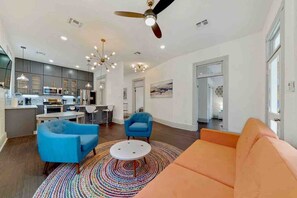 A modern living room with a sofa, chairs, a coffee table, and a kitchen in the background.