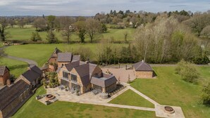 Un vaste domaine comprenant plusieurs bâtiments, une pelouse bien entretenue et, au loin, un terrain de golf.