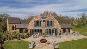 Une grande maison en briques dotée d’un vaste patio, d’un espace salon extérieur et d’un foyer.