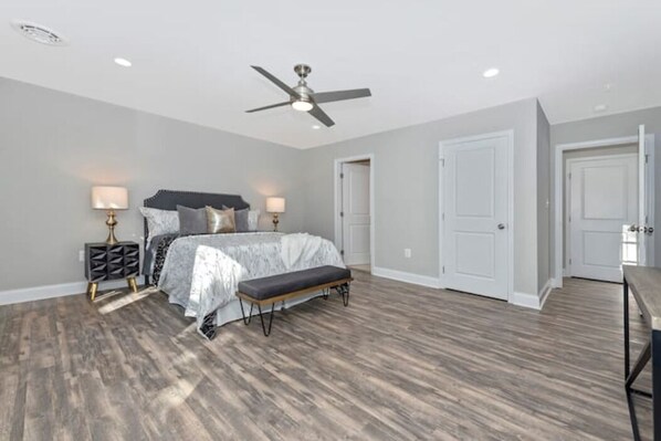 A bedroom with a bed, bedside tables, a ceiling fan, and a bench.
