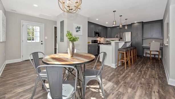 A modern kitchen with grey cabinets, a central island, and pendant lighting.