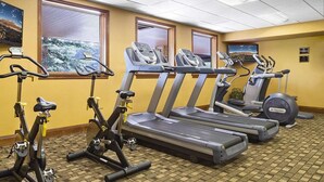 Un gimnasio con cintas de correr, bicicletas estáticas y elípticas.
