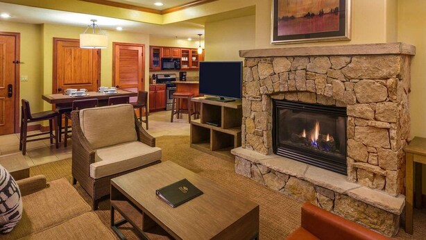 Una sala de estar con chimenea de piedra, un televisor y un comedor al fondo.