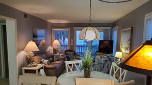 A living room with a sofa, chairs, a round table, a TV, and a lamp. - Direct Oceanfront 3 bedroom 2.5 baths Pelicans Watch unit on popular Shore Drive (Myrtle Beach)