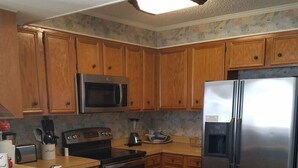 A kitchen with wooden cabinets, a stainless steel refrigerator, a microwave, a toaster, and a blender. - Direct Oceanfront 3 bedroom 2.5 baths Pelicans Watch unit on popular Shore Drive (Myrtle Beach)