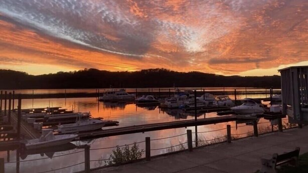 Un puerto deportivo al atardecer con barcos amarrados, un muelle y un edificio a la derecha.