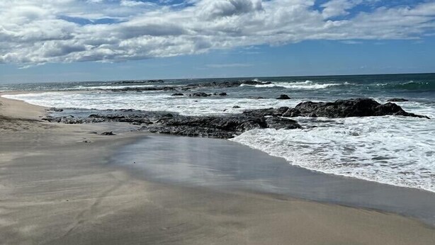 A beach with a rocky shoreline and waves crashing onto the sand.