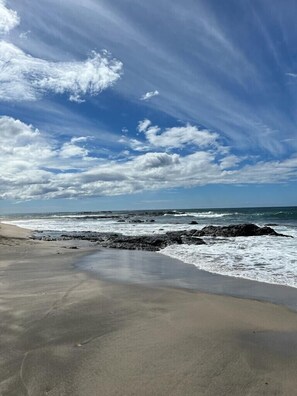 A beach with a rocky shoreline and waves crashing onto the sand.
