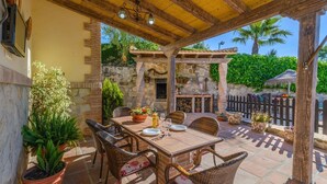 An outdoor patio with a stone wall, wicker furniture, and potted plants. - Villa Antisa Villanueva de la Concepción by Ruralidays (Málaga)