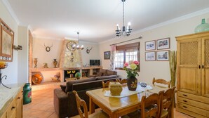 A cozy living room with a fireplace, a sofa, a dining table with chairs, and a TV. - Villa Antisa Villanueva de la Concepción by Ruralidays (Málaga)