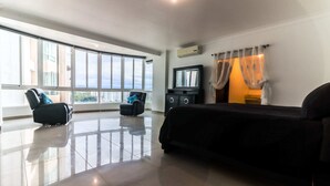 Un dormitorio moderno con un ventanal grande, una cama, un televisor y un armario negro.