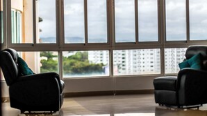 Una habitación con dos sillas negras, un ventanal con vistas a edificios y follaje, y una decoración de diseño moderno.