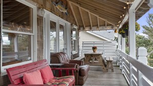 A covered porch with a wooden bench, a cushioned sofa, and a small table.