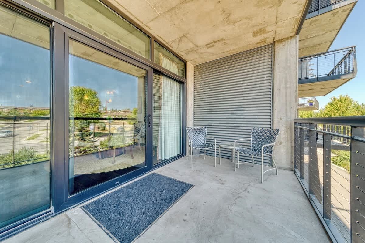 A balcony with a view of the city, a sliding glass door, and a metal railing.