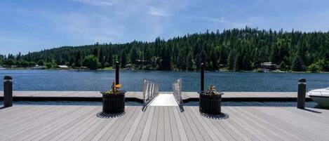 A wooden dock leading to a calm lake with dense forest in the background.