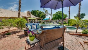 Un patio con piscina, mobiliario exterior y una zona de estar cubierta.