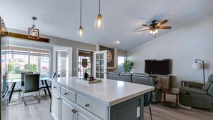 Una cocina amplia con una isla grande, un comedor con sillas, un sofá y un televisor.