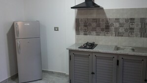 Eine Küche mit Kühlschrank, Gasherd und einer gefliesten Spritzschutzwand.