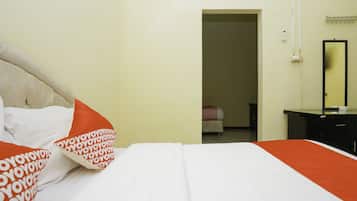 A hotel room with a bed, a bedside table, a mirror, and a door leading to another room.