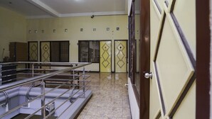 A hotel lobby with a reception desk, a staircase, and a door with a geometric pattern. - Oyo 2902 Graha 18 (Surabaya)