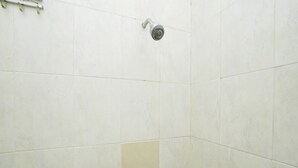 A shower area with white tiles and a corner tile design. - Oyo 2902 Graha 18 (Surabaya)