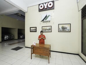 A person standing in front of a wall with the 'OYO' logo and three framed artworks. - Oyo 2902 Graha 18 (Surabaya)