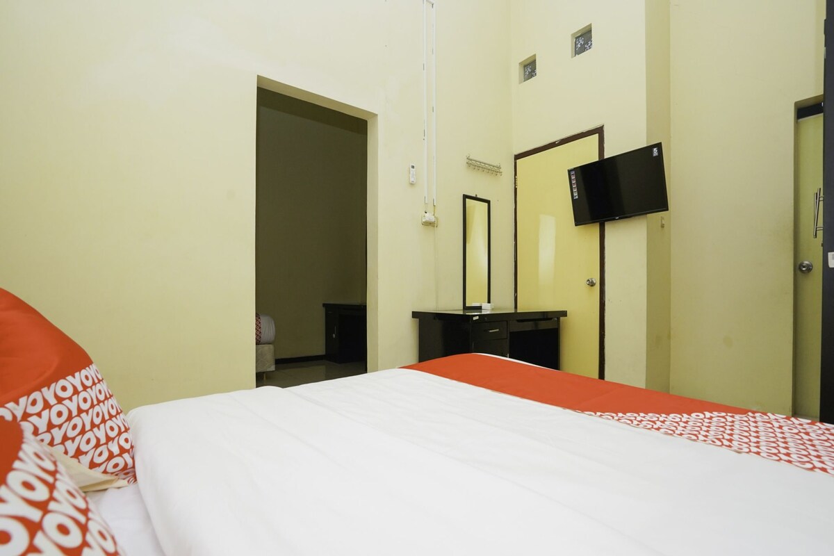 A hotel room with a bed, a desk, a TV, and a door.