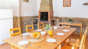 A wooden dining table set for breakfast with a stone fireplace in the background.