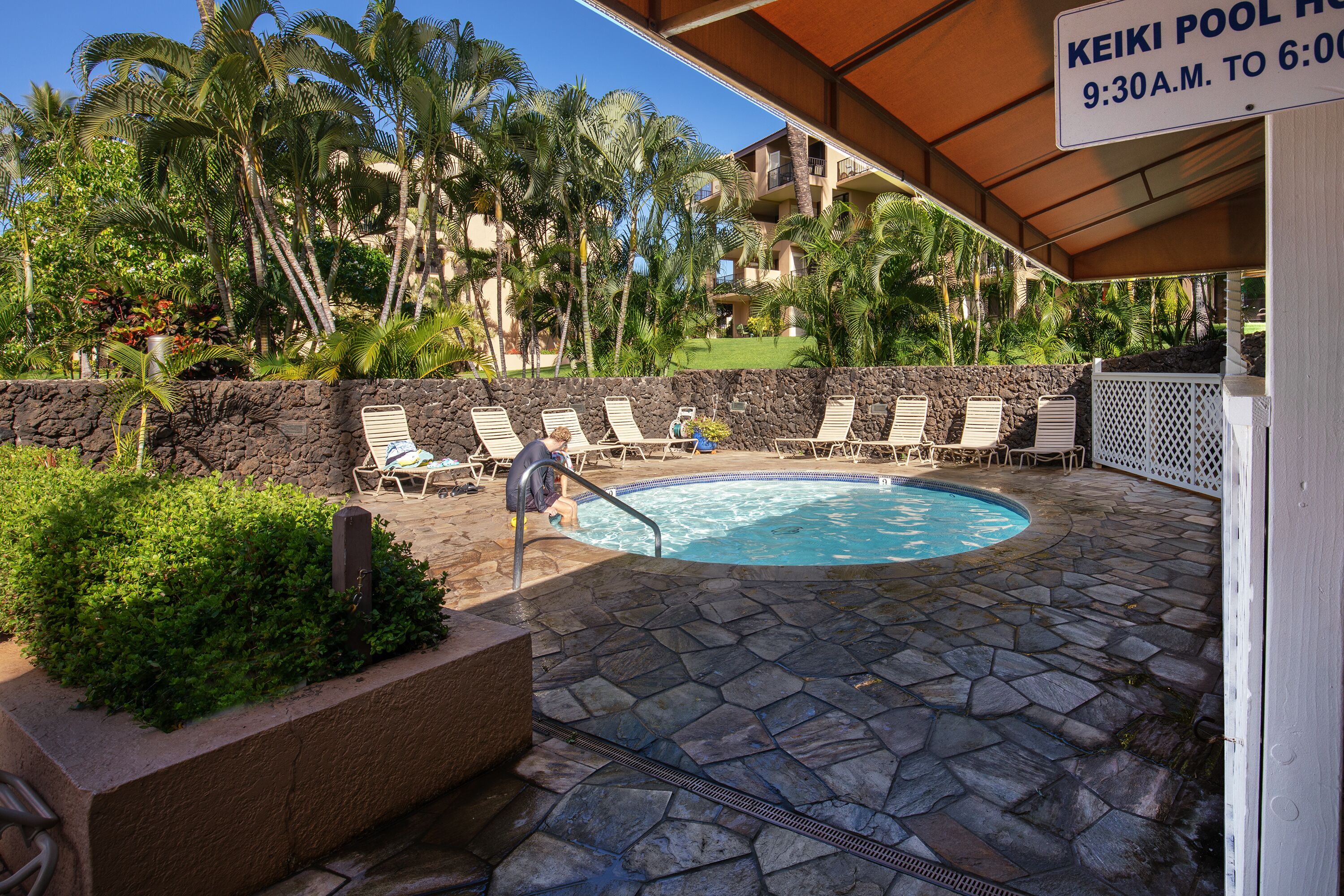 A pool area with lounge chairs and a stone wall.