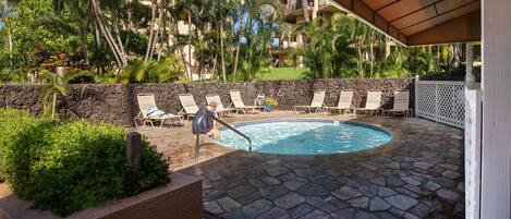 A pool area with lounge chairs and a stone wall.